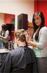 Portrait of a young woman cutting a man's hair with scissors