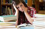 Depressed student surrounded by books looking at the camera