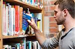 Male student picking a book in a library