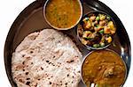Traditional Indian cuisine vegetarian thali served in small bowls on a round tray.