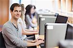 Smiling fellow students in an IT room with the camera focus on the foreground