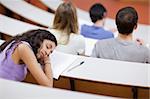 Young student sleeping during a lecture in an amphitheater