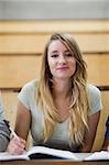 Portrait of a cute student holding a pen in an amphitheater