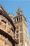 Detail of La Giralda Tower and Seville Cathedral. The bell tower (La Giralda) was previously a minaret of the Berber Almohad period in Spain. After the town was conquered by Christians, during the Reconquista period, the minaret was transformed and  in 1401 became the bell tower of the gothic and baroque Cathedral of Seville.