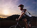 sports activity: young adult cyclist riding mountain bike in the countryside. Horizontal shape, side view, copy space