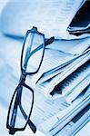 Newspapers and black glasses against a white a background