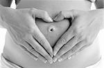Détail de la femme enceinte formant la forme coeur avec les mains