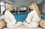 Two Women Relaxing By Swimming Pool