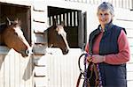 Senior Woman Standing By Stables