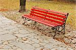 The old red wooden bench in the autumn park