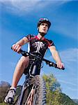 sports activity: young adult cyclist riding mountain bike in the countryside. Vertical shape, low angle view, copy space