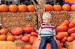 playful caucasian toddler sitting on the huge pumpkin