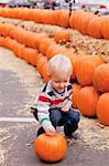adorable caucasian toddler picking up a pumpkin