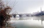 Foggy winter landscape with river and bridge