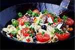 fresh pasta with tomatos and olives in a pan