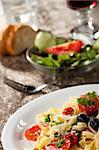 fresh pasta with tomatos and olives on a plate