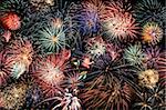 Multiple bursts of multicolored fireworks fill the horizontal frame against a black background