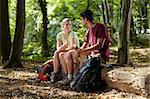 young man and woman having lunch with sandwich during hiking excursion. Horizontal shape, full length