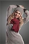 beautiful blonde curly girl in a winter fashion portrait wearing grey wool and a red scarf