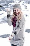 pretty young girl with curly blond hair in winter dress with hat and scarf playing and laughing to the camera