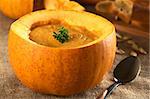 Fresh creamy pumpkin soup served in a pumpkin and garnished with parsley (Selective Focus, Focus on the parsley)