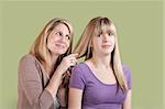 Smiling Caucasian mom with annoyed daughter over green background