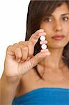 Young woman holding pills, isolated on white