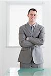 Business man standing behind table with his arms folded and smiling