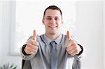 Young and happy businessman giving thumbs up