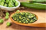 Raw split pea on wooden spoon with fresh green peas in the back (Selective Focus, Focus on the split peas one third into the spoon)