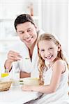 A girl eating breakfast with his father