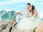 Bride kissing groom on the rock. Mountain on background