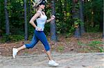 A young female jogger running through the woods