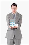 Portrait of a businessman looking at a miniature house against a white background