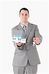 Portrait of a smiling businessman showing a miniature house and keys against a white background