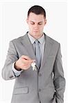 Portrait of a young businessman looking at a set of keys against a white background