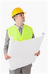 Portrait of a young builder looking around while holding a plan against a white background