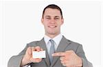 Smiling businessman pointing at a blank business card against a white background