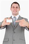 Portrait of a businessman pointing at a blank business card against a white background