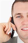 Close up of a young businessman making a phone call against a white background