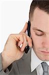 Close up of a tired businessman making a phone call against a white background