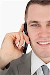 Close up of a smiling businessman making a phone call against a white background