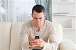 Man sending text messages while sitting on his couch in his living room