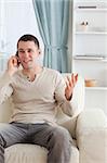 Portrait of a man talking through the phone while sitting on a couch in his living room