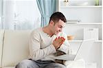 Happy man using a notebook in his living room