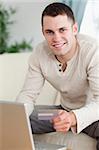 Portrait of a man using a laptop to book holidays in his living room