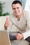 Portrait of a man purchasing online with the thumb up in his living room