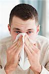 Portrait of a man blowing his nose in his living room