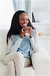 Smiling woman on sofa with a cup