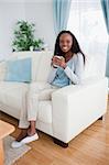 Smiling woman sitting on sofa with a cup